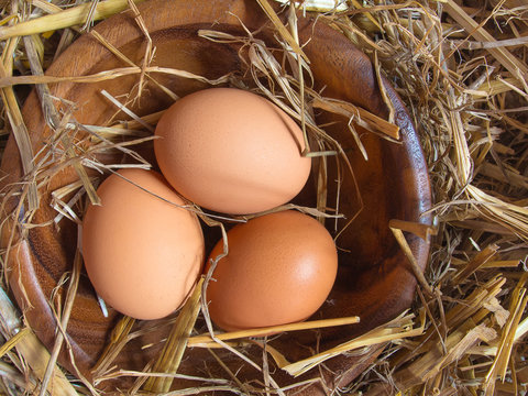 Fresh brown chicken eggs on a background of hay and straw in a rustic rural old style. The view from above is a flat horizontal