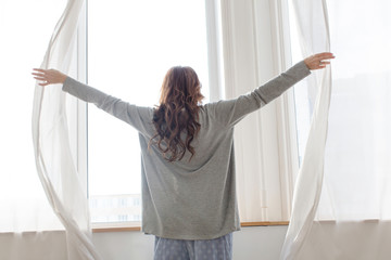 Female opens the curtains in the morning