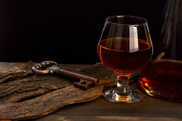 glass, carafe with cognac, whiskey and key on wooden table