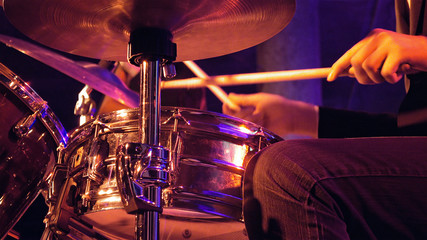 Fototapeta na wymiar Drummer plays on drum set and cymbal with drumsticks on the stage. Jazz or rock concert performance entertainment. Close up shot with soft selective focus.