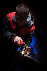 Young man working with plasma cutter on steel plate