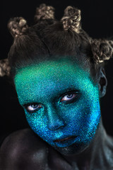 Portrait of beautiful woman with green and blue sparkles on her face. Glitter makeup