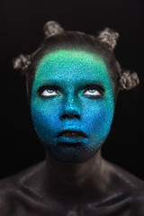 Portrait of beautiful woman with green and blue sparkles on her face. Glitter makeup