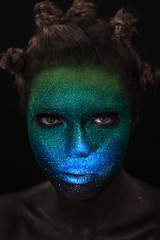 Portrait of beautiful woman with green and blue sparkles on her face. Glitter makeup.