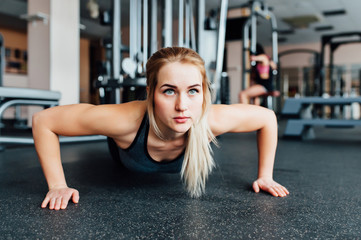Fototapeta na wymiar A woman trains in the gym performs plank exercise