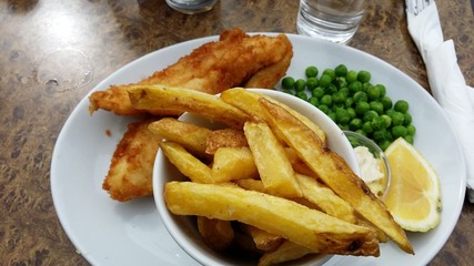 Fish, chips and peas with a glass of water on a table
