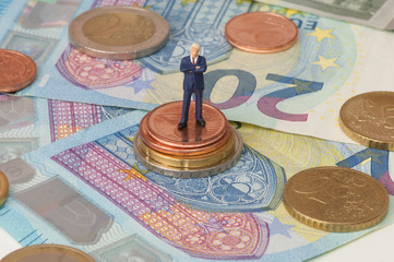 Mann im Anzug, stehend auf Geldmünzen, Geldscheinen