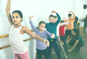 Young ballet dancers exercising in ballroom