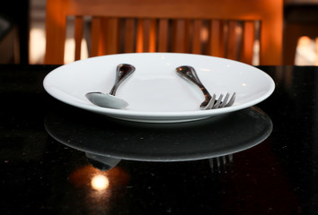 White dish, spoons, forks on black table 