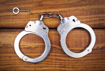 Steel metallic handcuffs on a wooden table