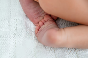 Newborn baby feet folded under the ass.