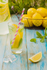 lemonade with mint on rocks served in a glass with a straw