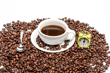 Coffee beans with cup of coffee and small alarm clock