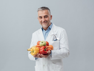 Smiling nutritionist holding fresh vegetables and fruit