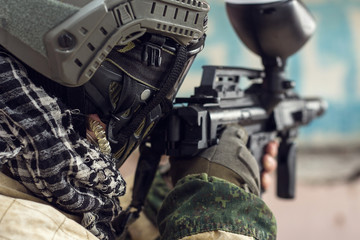 Crop shot of militaty man taking aim with paintball weapon