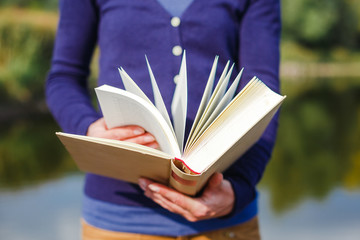 Close-up of female hands holding open book. Reading concept