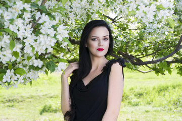 Beautiful young woman in blooming spring garden with white flowers, professional make-up