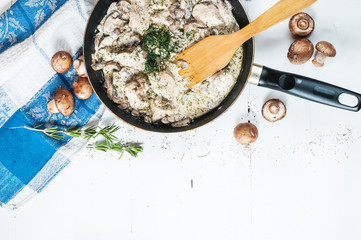 Chicken breast with mushrooms in cream sauce on a pan on the table.