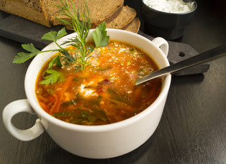 Beet soup in wooden plate with vegetables on wooden table. Borch, traditional Russian food
