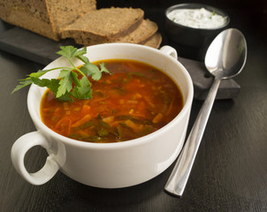 Beet soup in wooden plate with vegetables on wooden table. Borch, traditional Russian food