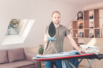 Handsome man ironing shirt at home