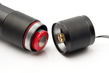 black flashlight opening the tail cap and have red alkaline battery inside on white background