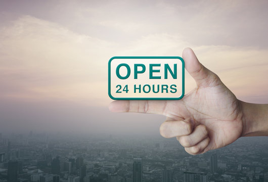 Open 24 hours icon on finger over city tower at sunset, vintage style