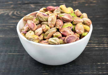 Pistachio nuts without a shell in a bowl on a wooden background