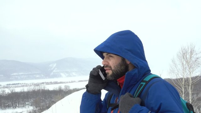 Traveler With a Beard Talking Smartphone On Mountain.