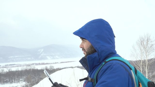 Traveler With a Beard Using Tablet On Mountain.