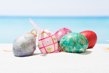 Easter on tropical beach background. Eggs on the white sand. Vacation and travel concept