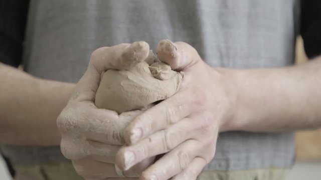 Pottery and ceramic. Adult male sculptor master preparing the clay in hands. Working with clay, manufacturing of clay sculpture figurines. Handmade art creation. Copy space text.