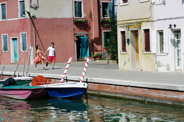 Fototapeta na wymiar Young couple holding hands walking in Burano, Venice, Italy