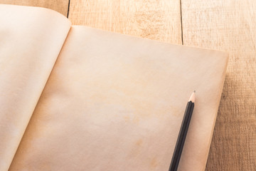 Old blank book open with pencil on the wood table