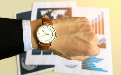 Watch on the left hand of business man with data report background for business and financial concept.