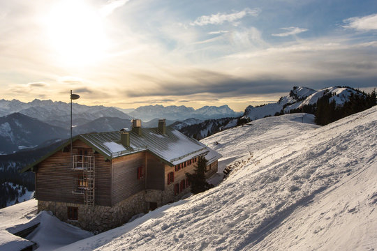 Brauneck Gipfelhaus in der D&auml;mmerung im Schnee mit Beegkulisse im Hintergrund, Brauneck, Bayern