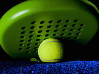 Closeup of a paddle racket, under a ball and on the playground carpet 