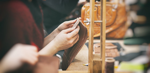 The young woman works with leather