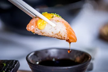 Selbstklebende Fototapeten Hands eat sushi with chopsticks © stockmelnyk