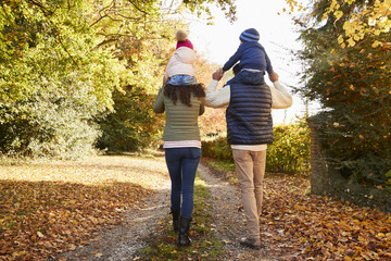 Fototapeta premium Autumn Walk With Parents Carrying Children On Shoulders