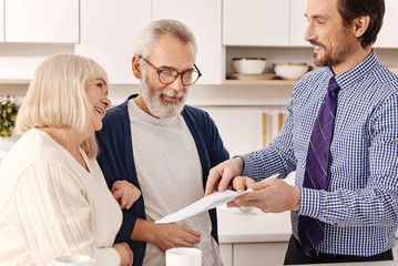 Cheerful aged couple owners meeting real estate agent at home