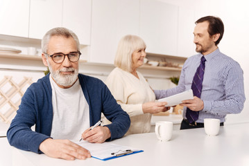 Bearded man signing agreement while his wife meeting notary