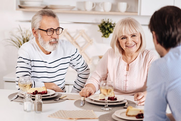 Fototapeta na wymiar Peaceful elderly couple relishing dinner with their kid at home