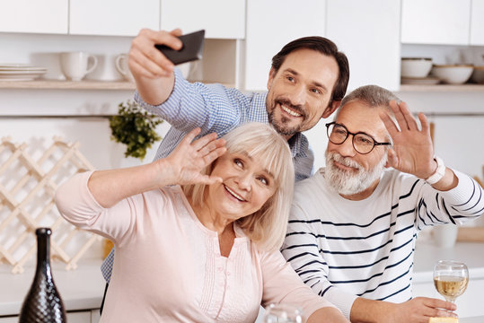 Smiling man taking selfie with senior parents at home