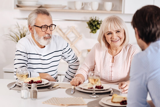 Peaceful elderly couple relishing dinner with their kid at home
