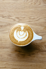 Latte with a drawing on  wooden table