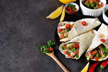 Mexican tacos with filling and guacamole sauce on a black background