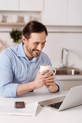 Happy mature man having conversation via Internet at home