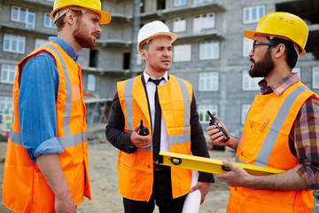 Young builders with walkie-talkies interacting at construction-site