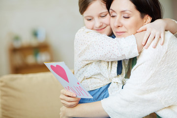 Girl and young woman in embrace reading greetings for mother day © pressmaster